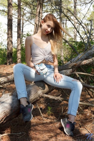 Девушка в дырявых голубых джинсах в лесу